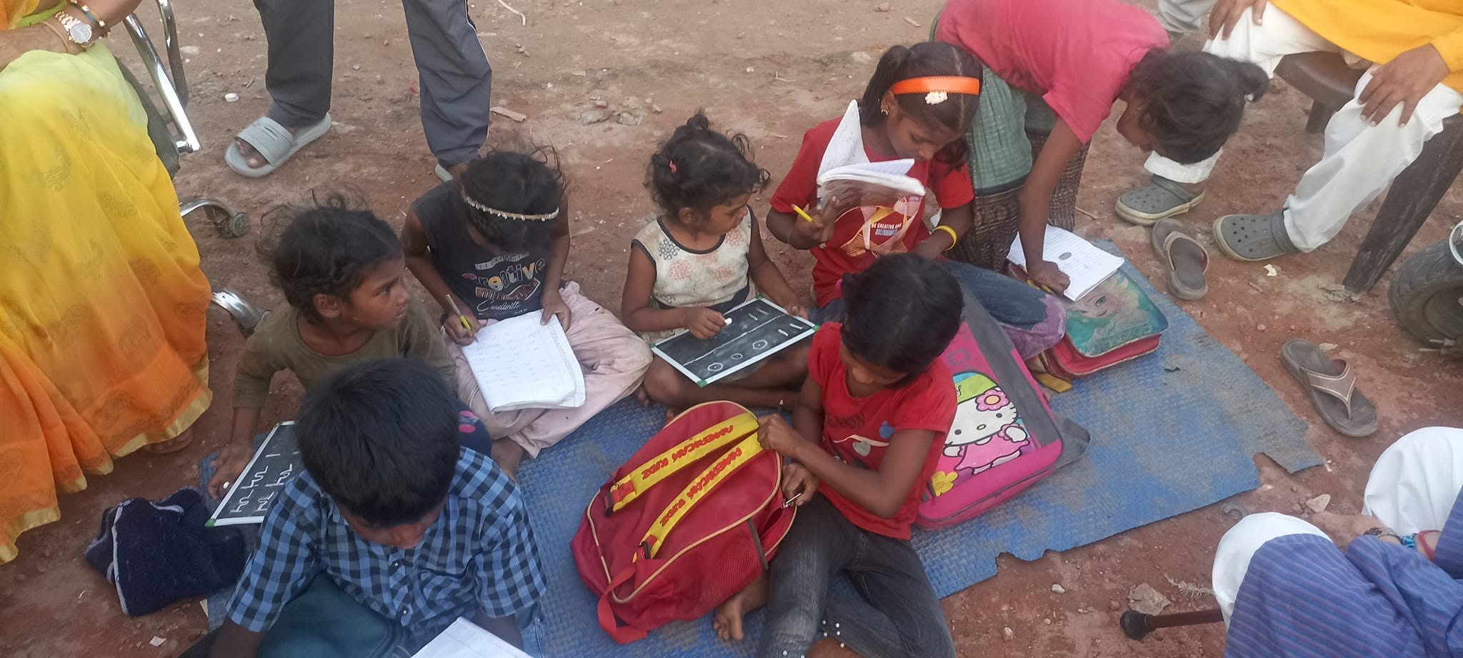 Slum children learning with notebooks on mat in Meerut